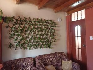 ein Sofa im Wohnzimmer mit Blumenarrangement an der Wand in der Unterkunft DEPA WANKA in Huancayo