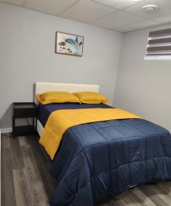 een slaapkamer met een bed met blauwe en gele lakens bij Entire Basement Suite with Private Entrance in Winnipeg