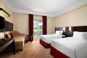 ローマにあるコートヤード バイ マリオット ローマ セントラル パークのベッド2台とソファが備わるホテルルームです。