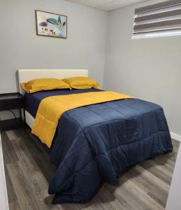 a bed with a blue and yellow comforter in a room at Entire Basement Suite with Private Entrance in Winnipeg