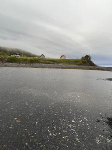 a body of water with buildings in the background at L’Asile de l’Anse-Pleureuse in Mont-Louis