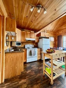 eine Küche mit Holzschränken und einem weißen Kühlschrank in der Unterkunft L’Asile de l’Anse-Pleureuse in Mont-Louis