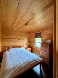 ein Schlafzimmer mit einem Bett in einer Holzhütte in der Unterkunft L’Asile de l’Anse-Pleureuse in Mont-Louis