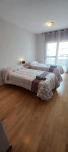 2 camas en una habitación con suelo de madera en Apartamento con 2 dormitorios, garaje y terraza junto a Valladolid en Valladolid