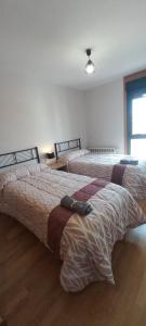 2 camas en una habitación de hotel con 2 colchas en Apartamento con 2 dormitorios, garaje y terraza junto a Valladolid en Valladolid
