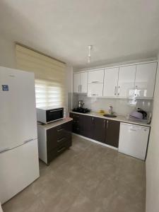 a kitchen with white cabinets and a white refrigerator at Kiralık Yazlık in Kuşadası