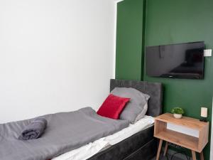a bed with a red pillow and a flat screen tv at SR24 - Stillvolles gemütliches Apartment 2 in Oer-Erkenschwick in Oer-Erkenschwick