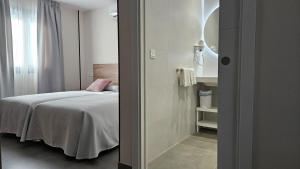 a small bedroom with a bed and a mirror at Apartamentos O Caneiro in Portomarin