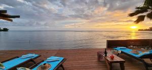 een houten terras met tafels en uitzicht op het water bij Villa Moana in Atiha