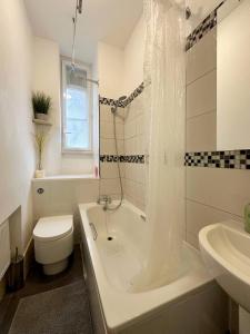 a bathroom with a tub and a toilet and a sink at Rowan’s Place in Holborn in London