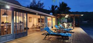 - une terrasse avec des chaises longues bleues sur le côté de la maison dans l'établissement Villa Moana, à Atiha