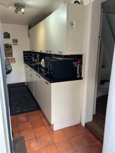 uma cozinha com armários brancos e um micro-ondas preto em The Hanging Gate Coach House em Madeley