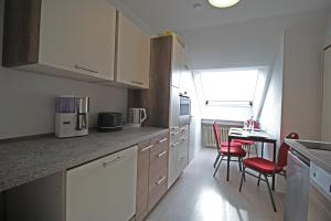 eine Küche mit weißen Schränken, roten Stühlen und einem Tisch in der Unterkunft Appartement im Bielefelder Westen in Bielefeld