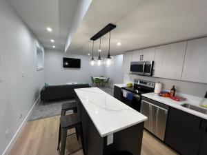 a kitchen and living room with a couch in the background at NEW Modern and Bright Suite near WEM in Edmonton