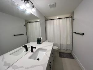 a white bathroom with a sink and a toilet at NEW Modern and Bright Suite near WEM in Edmonton