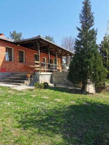 a house with a tree in front of it at Cottage House Official in Niš
