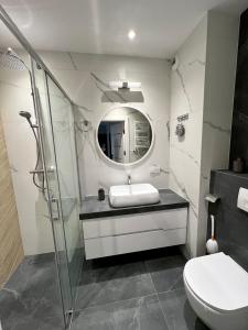 een badkamer met een wastafel en een glazen douche bij Apartament Orawska in Krakau