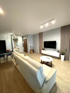 een woonkamer met een witte bank en een tv bij Apartament Orawska in Krakau