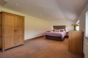 a bedroom with a bed and a wooden cabinet at Bramble, luxury in idyllic setting, at Hollambys in Groombridge