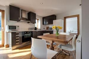 a kitchen with a wooden table and white chairs at Bramble, luxury in idyllic setting, at Hollambys in Groombridge