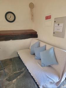 a couch with two blue pillows on it with a clock at Estúdio Tia Anica in Reguengos de Monsaraz