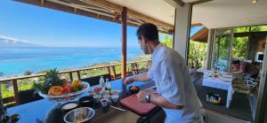 un hombre preparando comida en una mesa con vistas al océano en Villa Manatea, en Teavaro