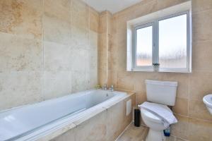 a bathroom with a tub and a toilet and a sink at StayRight 3 Bed House with Private Parking in Cardiff