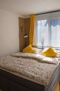 a large bed with yellow pillows and a window at Danube City Lodge, uptown, A/C in Vienna