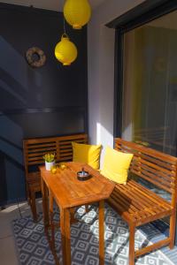 einen Holztisch und eine Bank mit gelben Kissen auf einer Terrasse in der Unterkunft Danube City Lodge, uptown, A/C in Wien