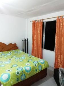 カリにあるapartamento auraのベッドルーム1室(ベッド1台付)、窓(オレンジ色のカーテン付)