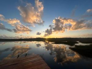 una puesta de sol en un lago con nubes en el cielo en Glamping Bio-Dorf Cabana 1, en Trairi