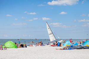 een groep mensen op een strand met een zeilboot bij Tiny house CC4 - it Soal Workum in Workum