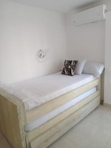 een bed in een kamer met een witte muur bij Apto peña azul la aldea in Ricaurte