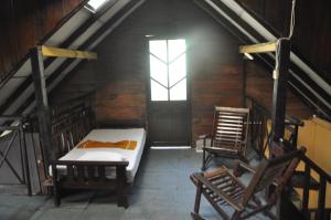 a attic room with a bed and two chairs at Tree House Rangala in Hunnasgiriya