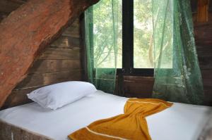a bed in a log cabin with a window at Tree House Rangala in Hunnasgiriya