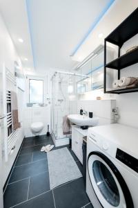 ein Badezimmer mit einer Waschmaschine, einem Waschbecken und einer Waschmaschine in der Unterkunft BellaBene modernes Studio Apartment in toller Lage mit Terrasse, Parkplatz, SmartTV in Pforzheim