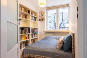 a bedroom with a bed and a window and bookshelves at Book a book - Apartment in the city center in Warsaw