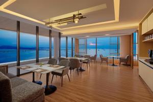 un restaurante con mesas y sillas y vistas al océano en Batam Marriott Hotel Harbour Bay en Nagoya
