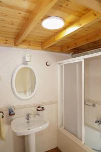 ein Bad mit einem Waschbecken, einem Spiegel und einer Dusche in der Unterkunft Casa en ruta de los faros costa da morte in Camelle
