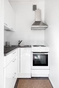 uma cozinha branca com um fogão e um lavatório em Studio Hätilänkatu em Hämeenlinna