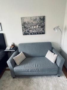 un divano blu in soggiorno con un dipinto di Mysiga rummet inne i Örebro a Örebro