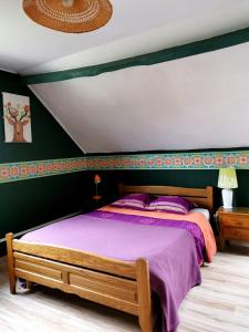 a bedroom with a large bed with purple sheets at Gite proche du Val Joly - 4911 - in Willies