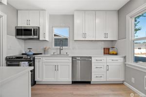 a white kitchen with white cabinets and a sink at Cozy Sumner Home, Shops & Dining Nearby in Sumner