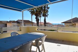 a blue table and chairs on a balcony with palm trees at Punta di Mola House in Marina di Ragusa