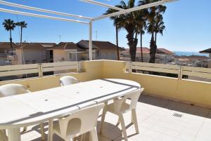a white table and chairs on a balcony with palm trees at Punta di Mola House in Marina di Ragusa