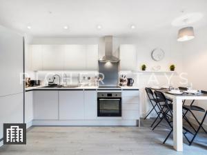 a kitchen with white cabinets and a table and a dining room at Cosy Studio Apartment- Hemel Hempstead High Street in Hemel Hempstead