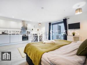 a bedroom with a large bed and a kitchen at Cosy Studio Apartment- Hemel Hempstead High Street in Hemel Hempstead