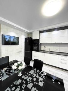 a kitchen with a table and chairs and a kitchen with white cabinets at Most City Area Pearl Apartment in Dnipro