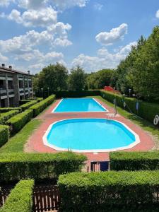 a large swimming pool in a garden with bushes at Appartamento Lago Playa in Desenzano del Garda