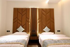 two beds in a hotel room with white sheets at كيان للأجنحة الفندقية- احد رفيده in Rabba